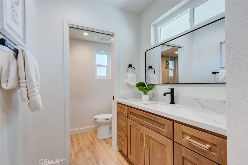 11919 Mayfield Avenue, Unit 2 Los Angeles, CA 90049 - Photo 38 of 75 a bathroom with a granite countertop sink a toilet and mirror