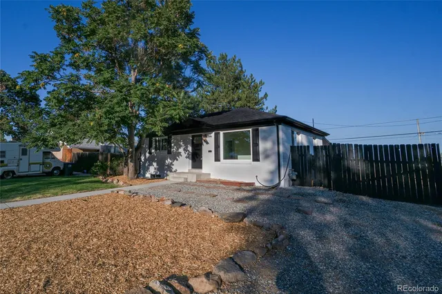 a front view of a house with a garden and trees