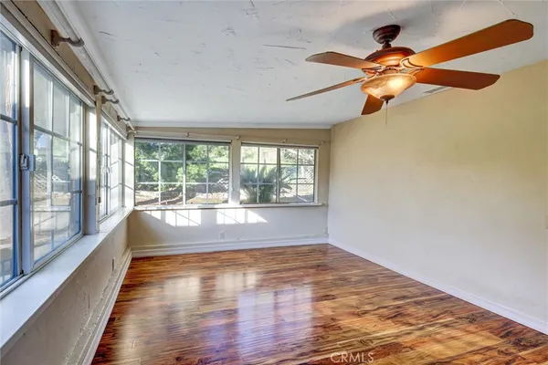 a view of empty room with wooden floor and fan