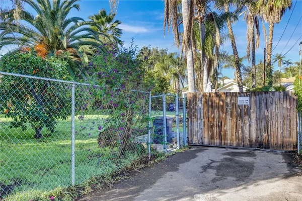 a view of a palm trees front of house with wooden fence