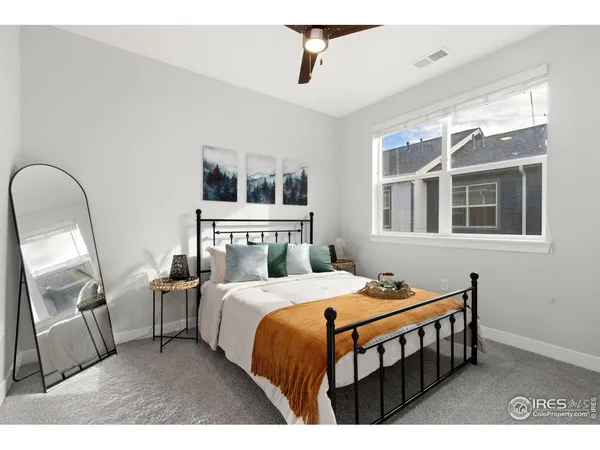 a bedroom with a bed a mirror on dresser and a window