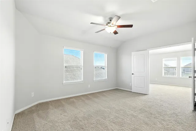 a view of an empty room with chandelier fan and fire place