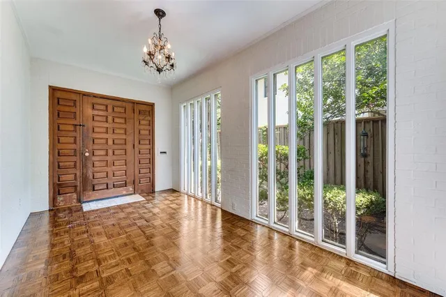 a view of an empty room with window and hardwood floor