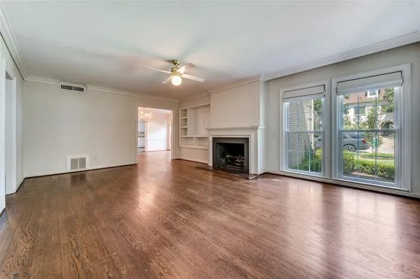an empty room with wooden floor fireplace and windows