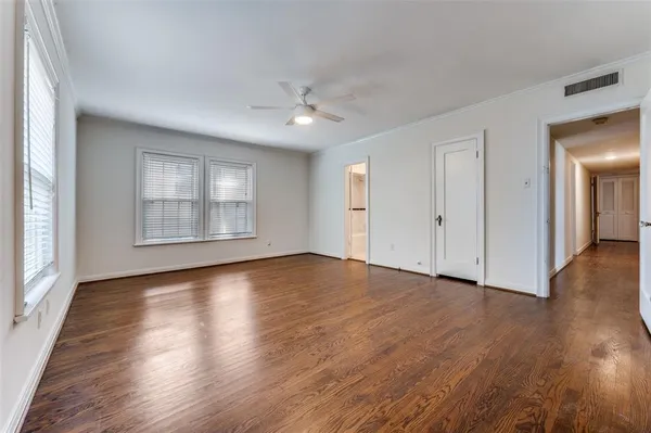 an empty room with wooden floor chandelier and windows