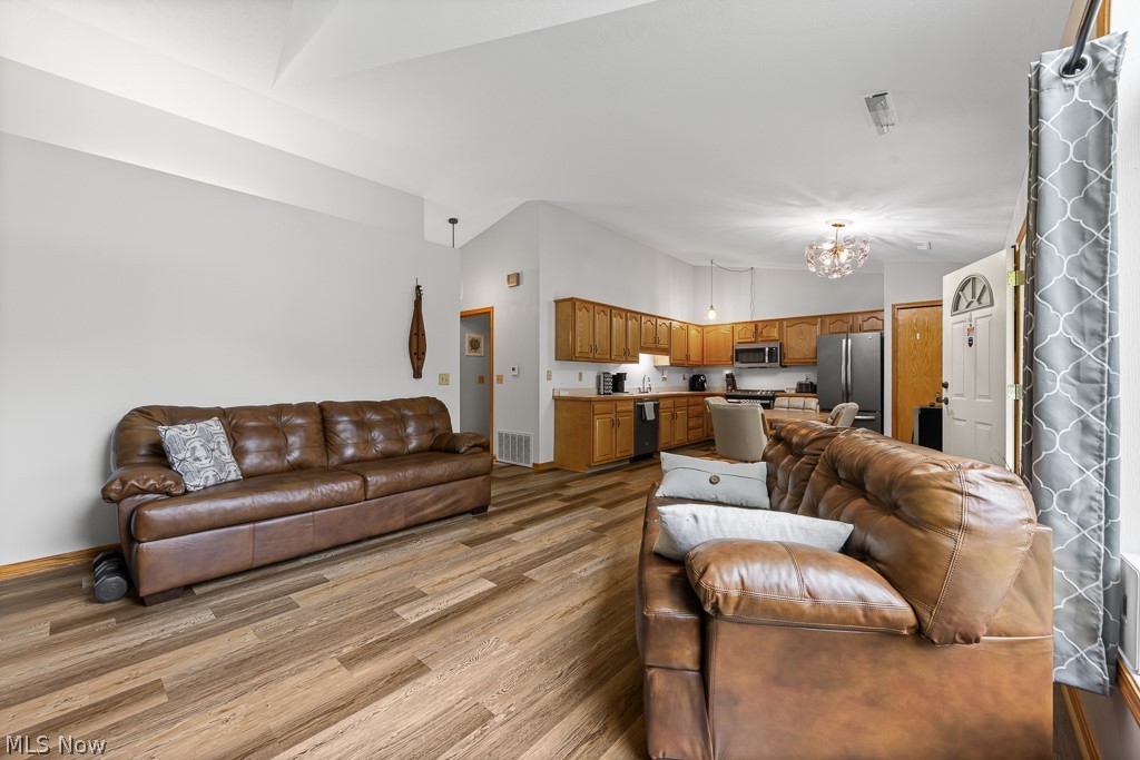 808 Ryan Road, Unit 14 Medina, OH 44256 - Photo 10 of 40 Vaulted ceilings elevate this open-concept living area featuring wood-finish flooring, a kitchen with light wood cabinetry, and stainless steel appliances