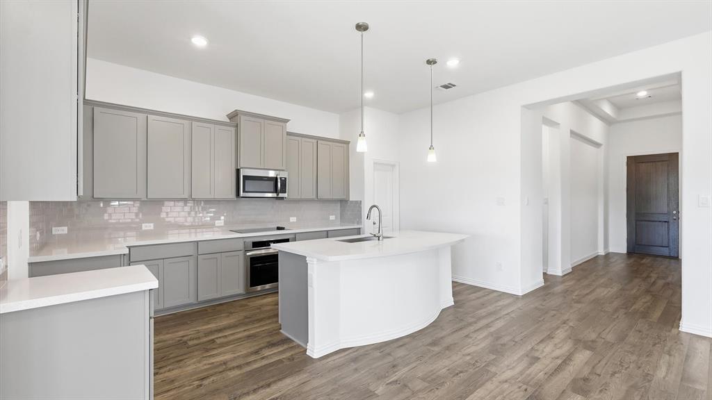 2529 Rivers W Road Anna, TX 75409 - Photo 19 of 40 Contemporary kitchen with light grey cabinetry, white countertops, stainless steel appliances, and a curved island featuring pendant lighting