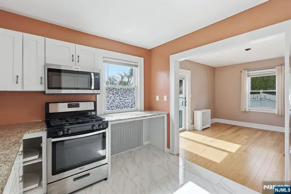 an empty room with wooden floor chandelier fan and windows