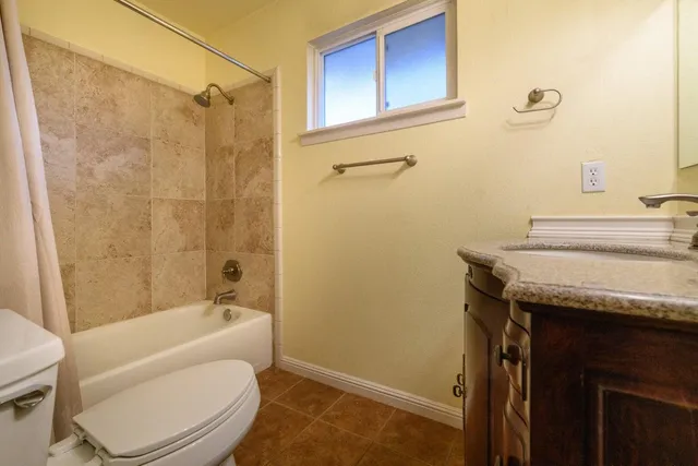a bathroom with a granite countertop bathtub sink vanity mirror and toilet