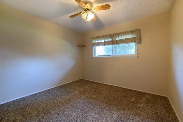 an empty room with a window and a fan