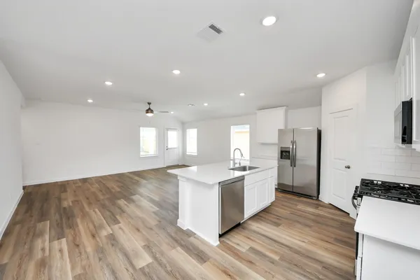 a kitchen with stainless steel appliances granite countertop a sink and a stove top oven with wooden floor