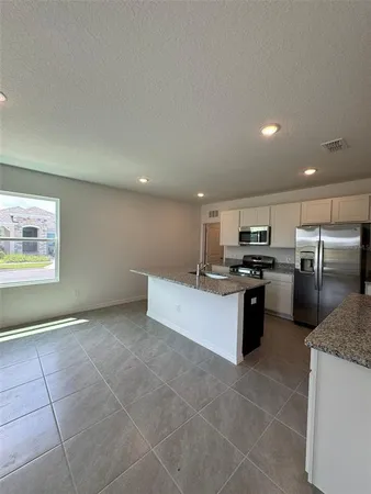 a large kitchen with a stove a sink a microwave and cabinets