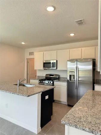 a kitchen with kitchen island a counter top space cabinets stainless steel appliances and a counter space