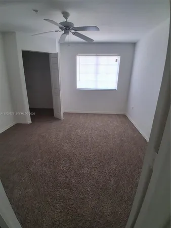 an empty room with windows and fan
