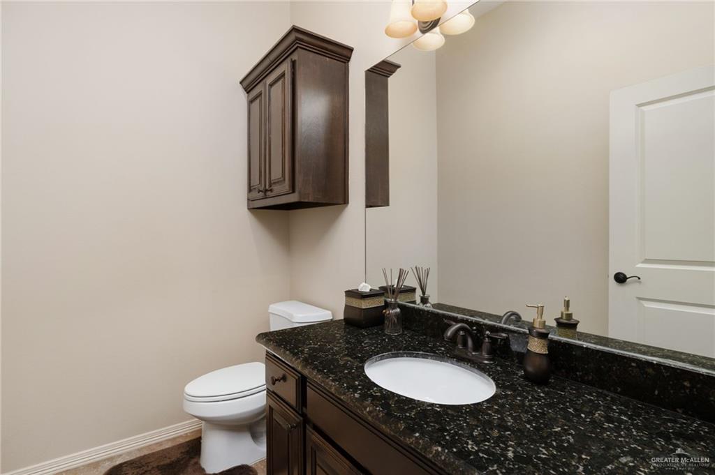 605 Ithaca Avenue McAllen, TX 78501 - Photo 15 of 23 a bathroom with a granite countertop sink a mirror and a toilet