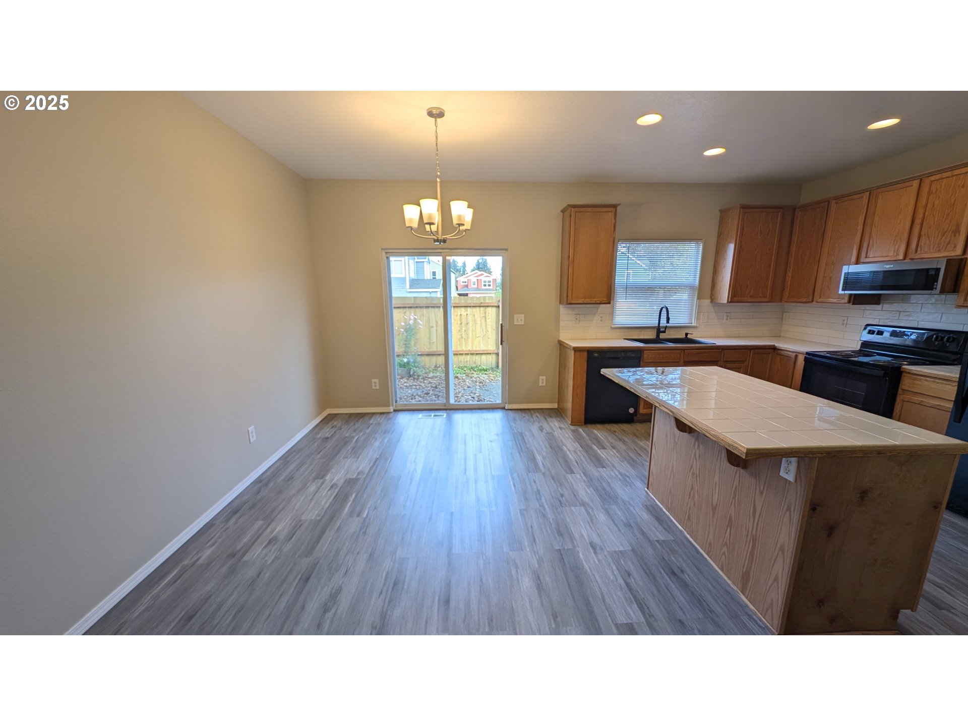 18541 Southwest Takena Court Beaverton, OR 97003 - Photo 6 of 24 a open kitchen with stainless steel appliances granite countertop a stove a refrigerator a sink a microwave oven with wooden floor and cabinets