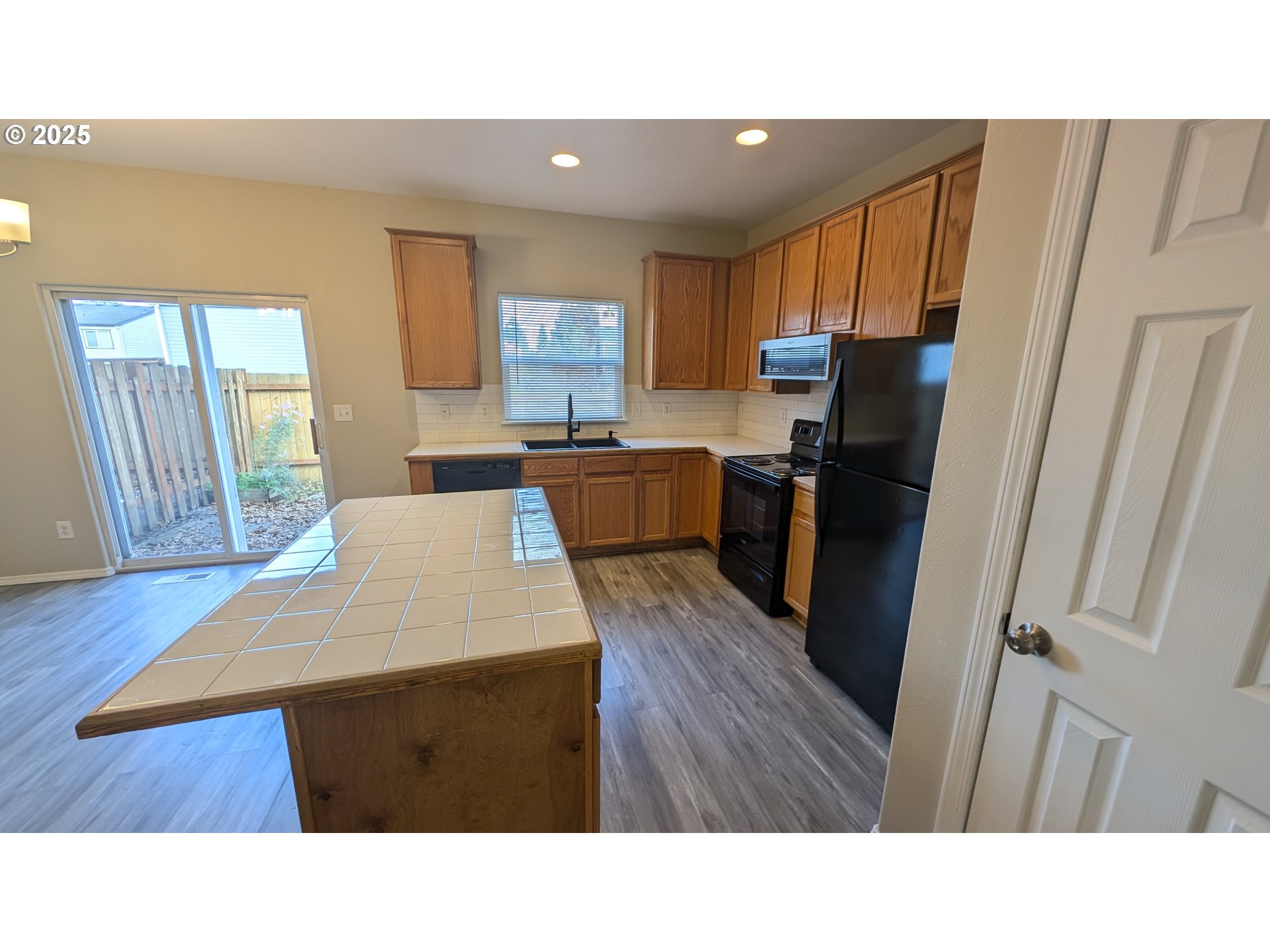 18541 Southwest Takena Court Beaverton, OR 97003 - Photo 9 of 24 a kitchen with a refrigerator a stove top oven a sink dishwasher and wooden cabinets with wooden floor