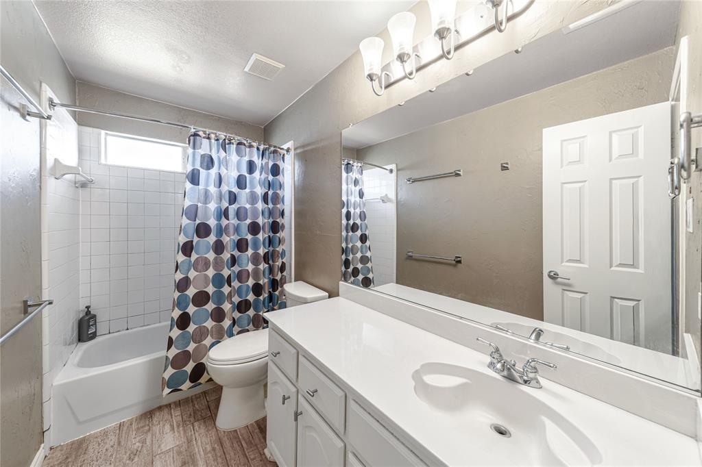 8001 St Fillans Lane Rowlett, TX 75089 - Photo 23 of 40 a bathroom with a sink a toilet a mirror a bathtub and shower