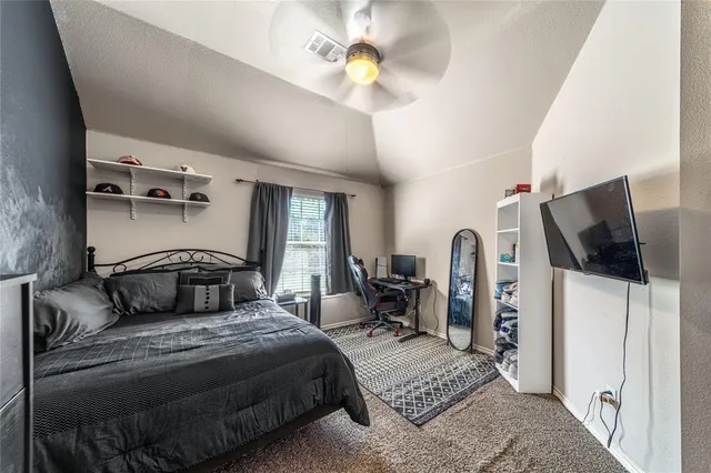 a bedroom with a bed and a flat tv screen on the dresser