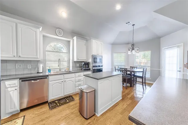 a kitchen with white cabinets and chairs