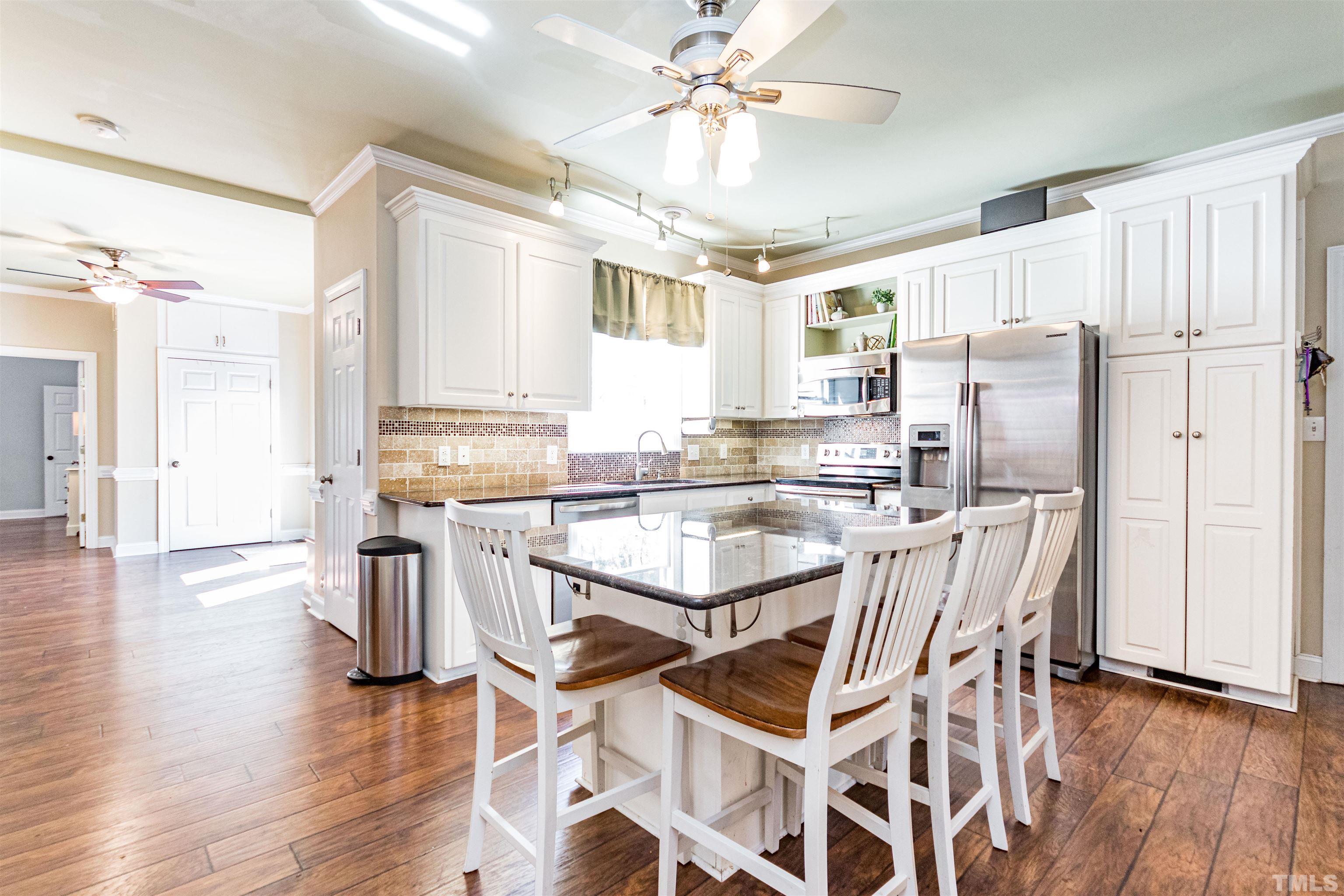 120 Kelsey Court Clayton, NC 27520 - Photo 15 of 62 a kitchen with stainless steel appliances a refrigerator a stove a sink dishwasher and white cabinets with wooden floor