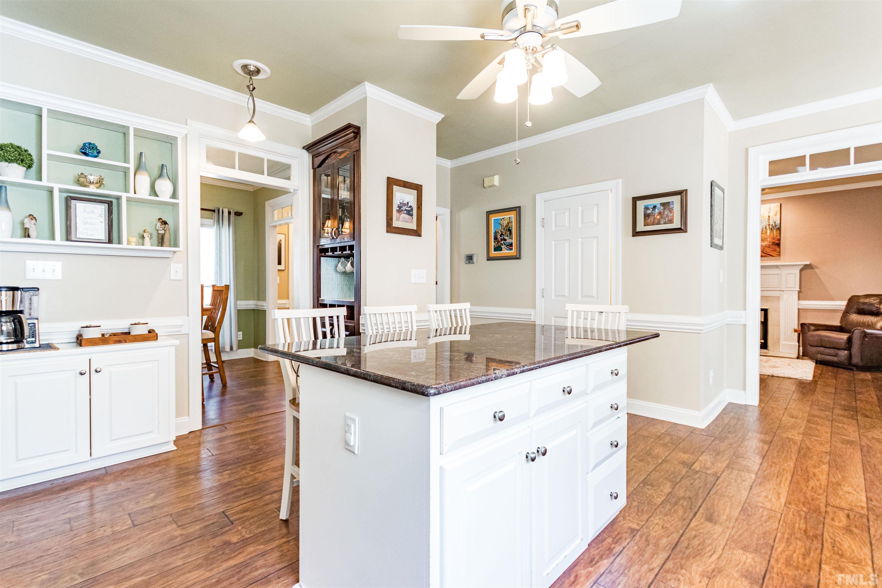 120 Kelsey Court Clayton, NC 27520 - Photo 16 of 62 a kitchen with granite countertop a microwave a stove and white cabinets with wooden floor