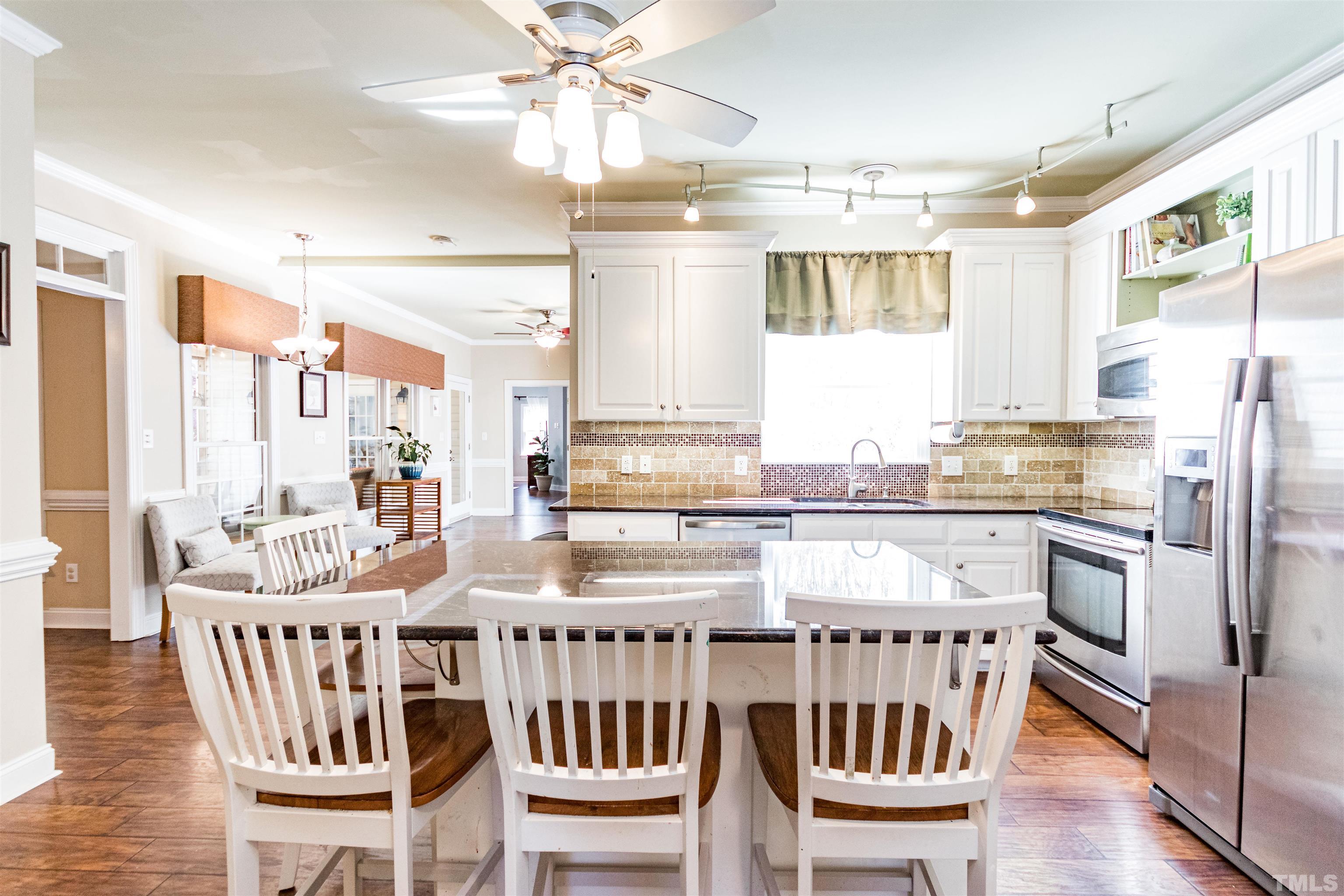 120 Kelsey Court Clayton, NC 27520 - Photo 18 of 62 a kitchen with stainless steel appliances granite countertop a stove a refrigerator a kitchen island and chairs