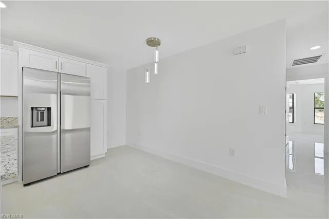 a view of a refrigerator in kitchen and white cabinets