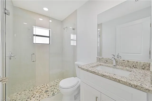 a bathroom with a granite countertop sink a toilet a shower and a mirror
