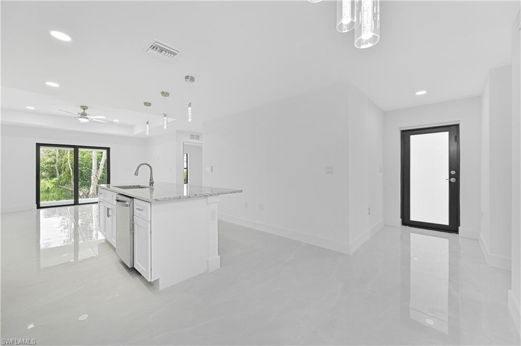 4709-4711 27th Street Southwest Lehigh Acres, FL 33973 - Photo 21 of 21 Kitchen with recessed lighting, light stone counters, hanging light fixtures, white cabinets, and open floor plan