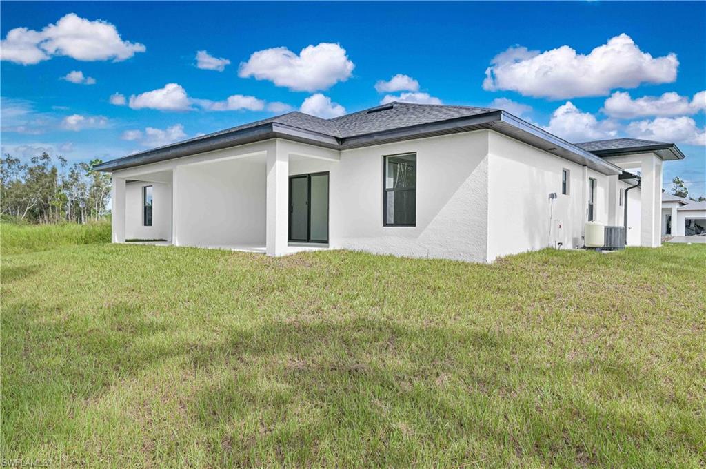 4709-4711 27th Street Southwest Lehigh Acres, FL 33973 - Photo 2 of 21 Back of house featuring stucco siding, a lawn, and a patio area