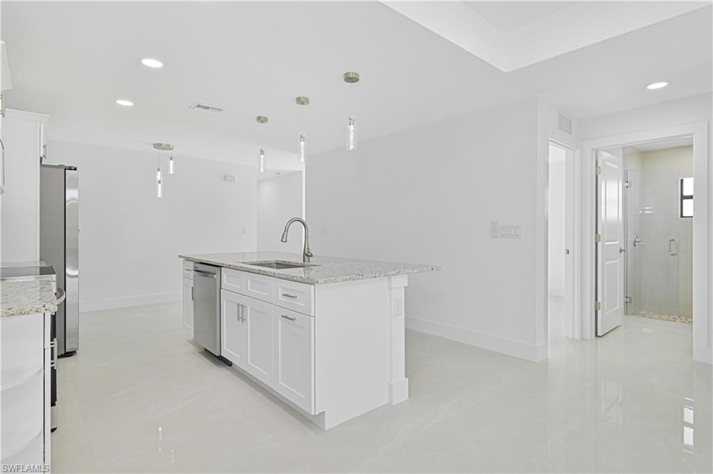 4709-4711 27th Street Southwest Lehigh Acres, FL 33973 - Photo 7 of 21 Kitchen with recessed lighting, white cabinetry, light stone counters, decorative light fixtures, and a kitchen island with sink