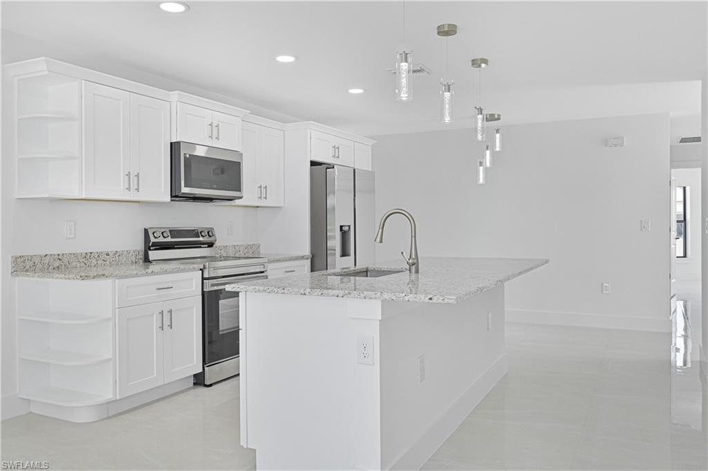 4709-4711 27th Street Southwest Lehigh Acres, FL 33973 - Photo 8 of 21 Kitchen with open shelves, stainless steel appliances, pendant lighting, white cabinetry, and light stone counters