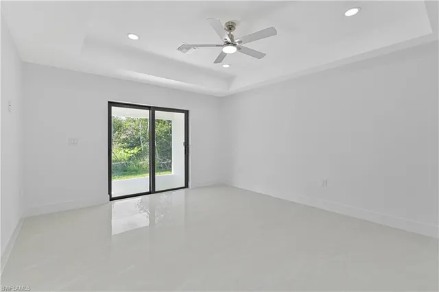 an empty room with windows and ceiling fan