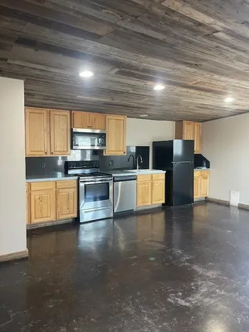 a kitchen with stainless steel appliances wooden cabinets a stove top oven a sink and dishwasher