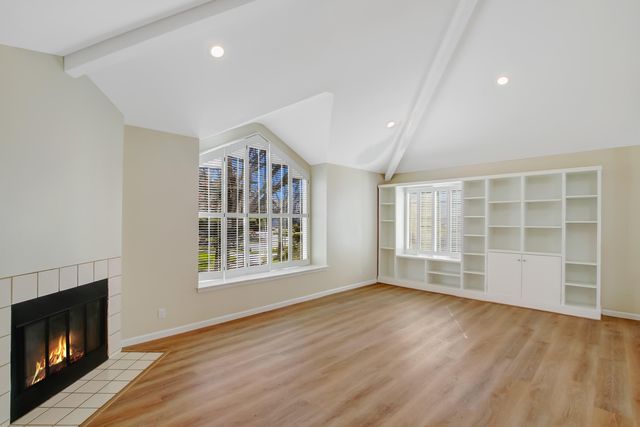 a view of an empty room with a window and fireplace