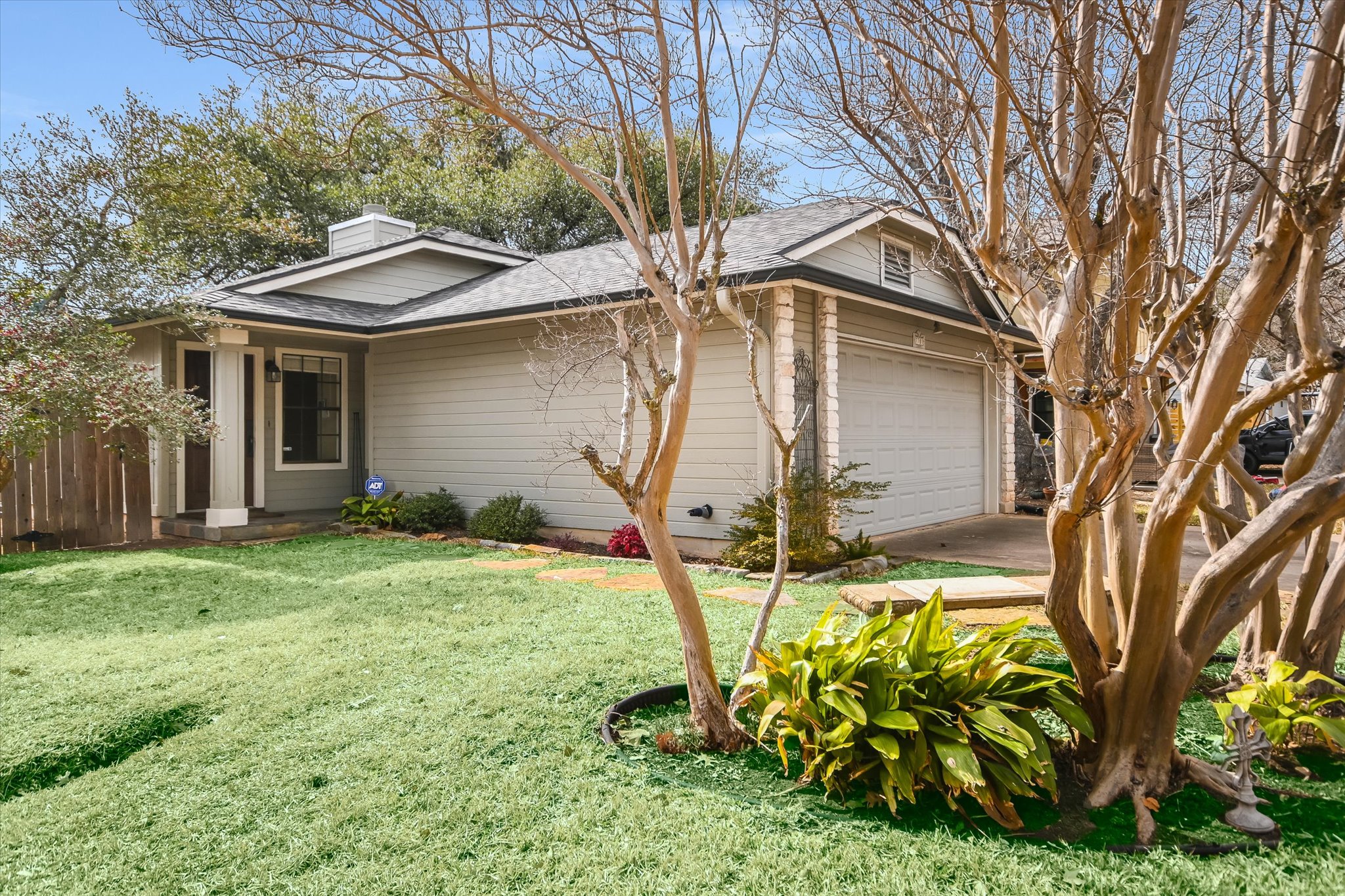 View of front facade featuring a front lawn, a garage, a chimney, roof with shingles, and driveway