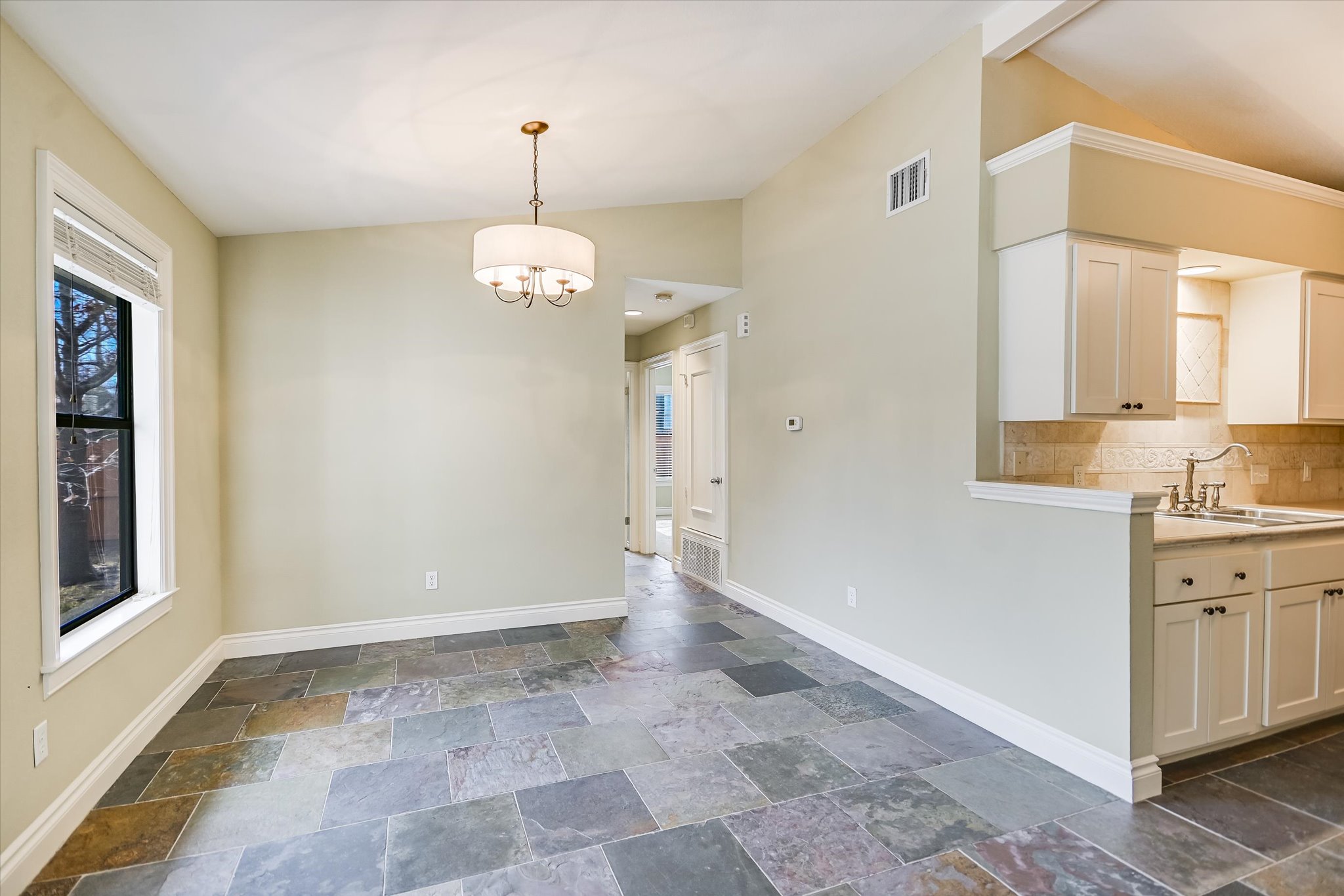 7701 Grovedale Trail Austin, TX 78729 - Photo 5 of 13 Unfurnished dining area featuring vaulted ceiling, stone tile flooring, and suspended lighting