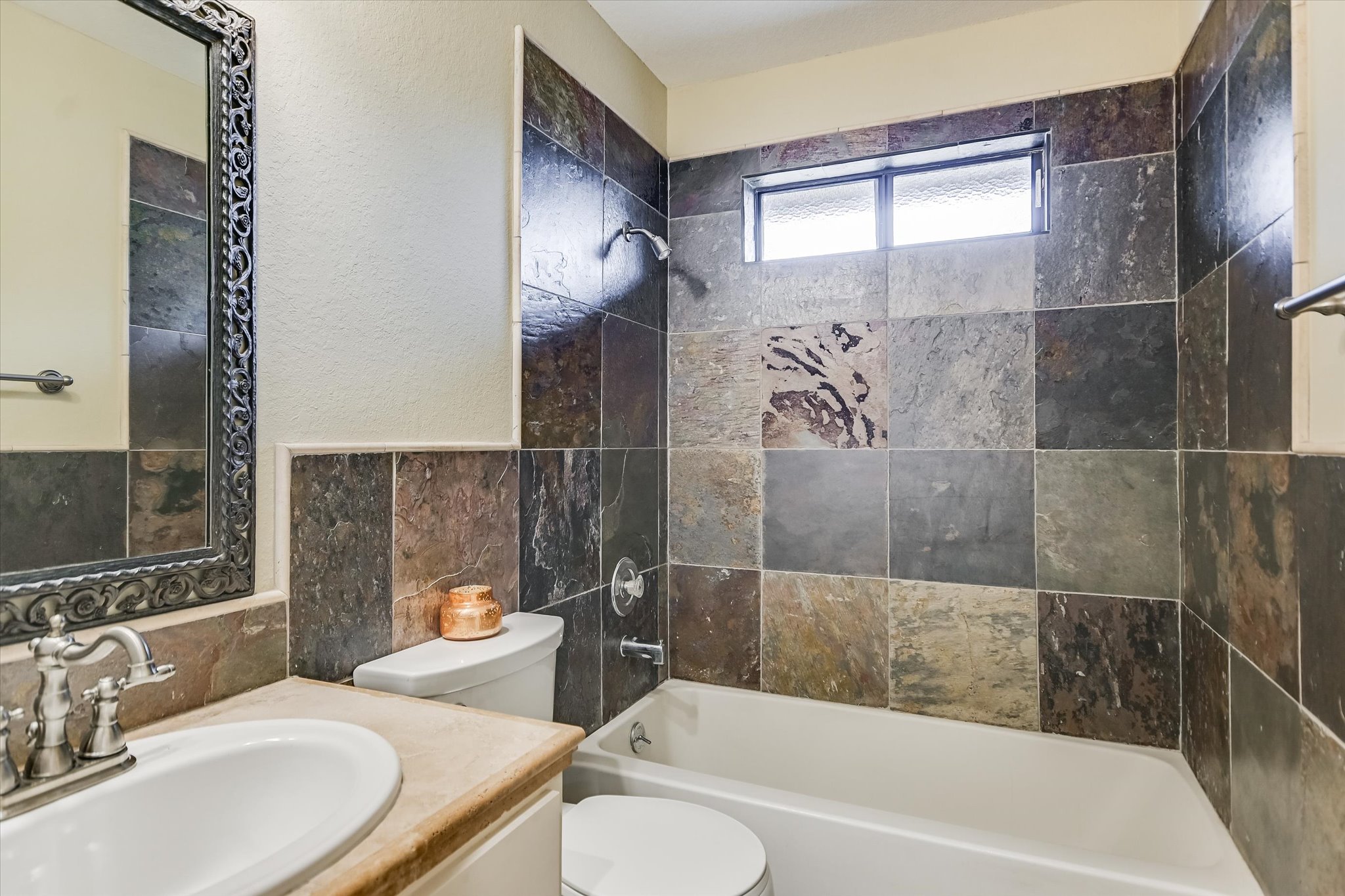7701 Grovedale Trail Austin, TX 78729 - Photo 10 of 13 Bathroom featuring shower combination, vanity, tile walls, a textured wall, and wainscoting