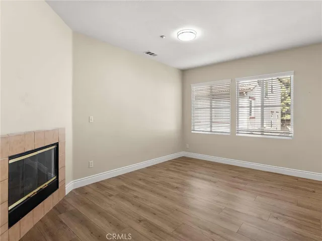 a view of an empty room with wooden floor fireplace and a window