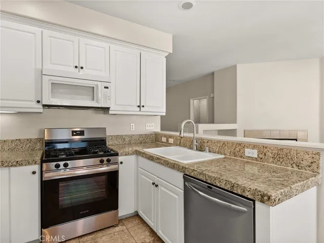 a kitchen with granite countertop a stove sink and cabinets