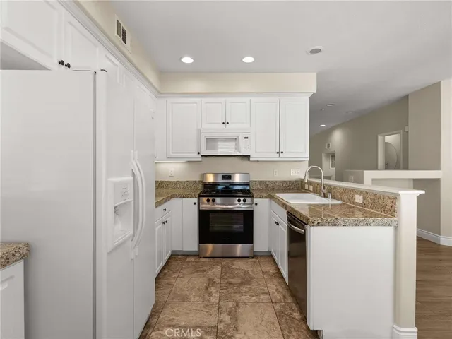 a kitchen with stainless steel appliances granite countertop a stove a sink and a refrigerator