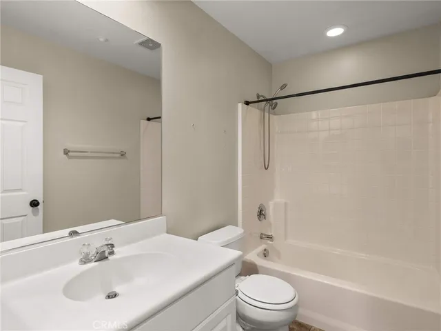 a bathroom with a bathtub shower sink mirror vanity and toilet