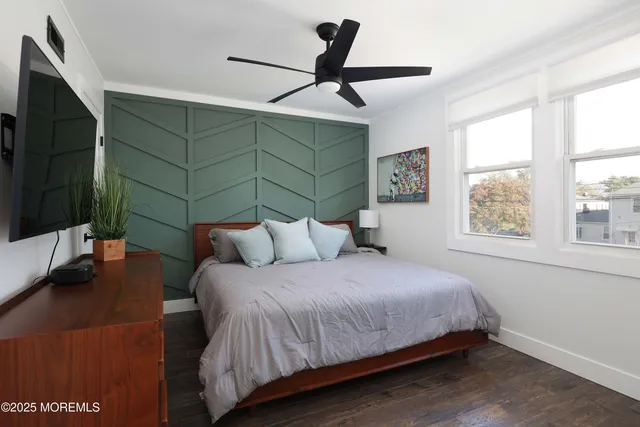a bedroom with a bed a window and a flat screen tv