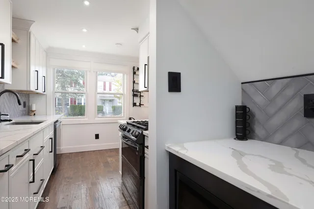 a kitchen with white cabinets and wooden floor