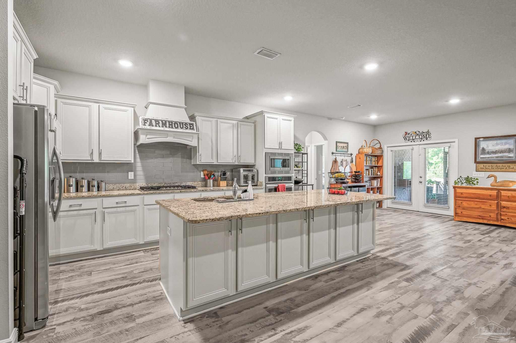 8056 Stream Ridge Road Pensacola, FL 32526 - Photo 6 of 71 a kitchen with stainless steel appliances a sink a stove a refrigerator cabinets and a center island