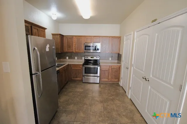 a kitchen with stainless steel appliances a refrigerator and a stove top oven