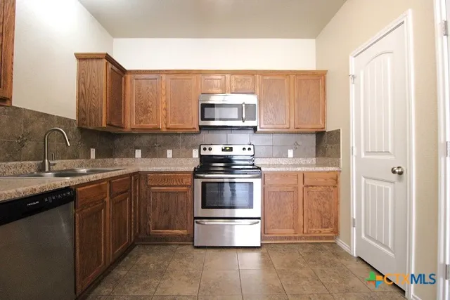 a kitchen with stainless steel appliances granite countertop a stove top oven a sink and dishwasher