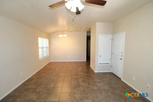 a view of an empty room with a chandelier fan