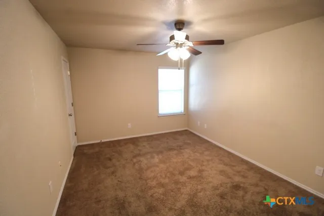 an empty room with a chandelier fan and windows
